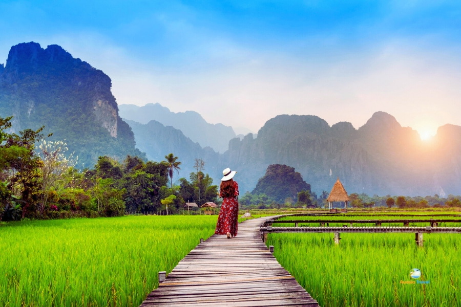 Tourist walking on wooden bridge at Vang Vieng rice fields Laos – Auasia Travel